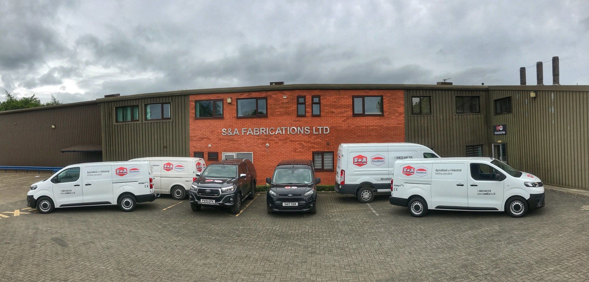 A group of vans are parked in front of a building.