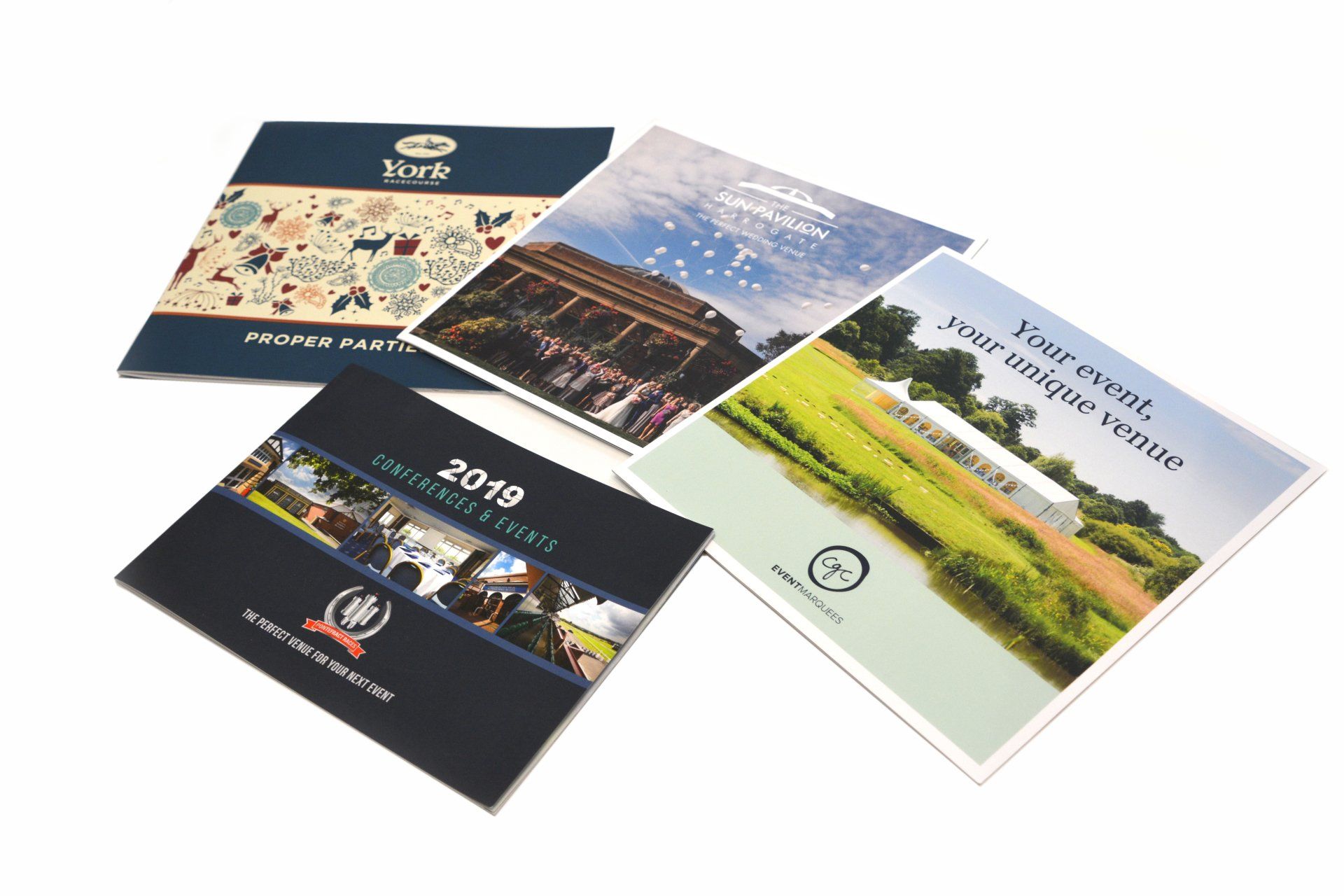Four brochures are stacked on top of each other on a white surface.