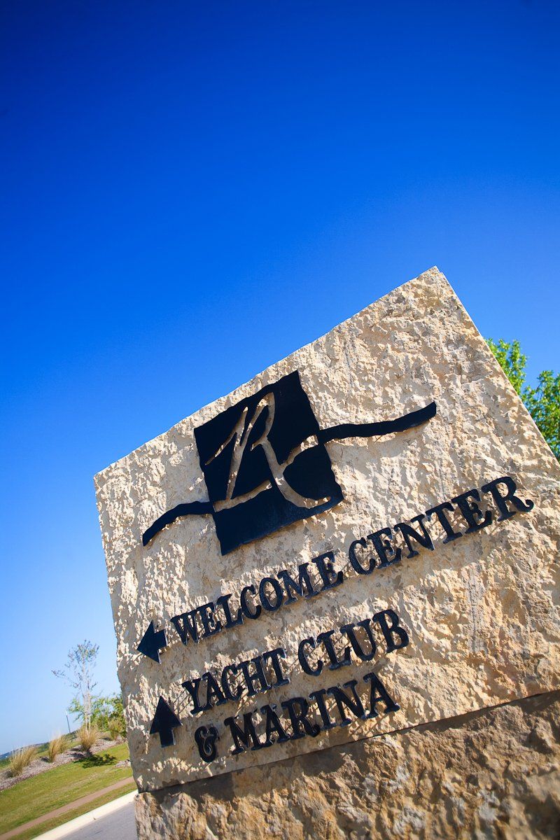 A tan stone sign against a blue sky, reading