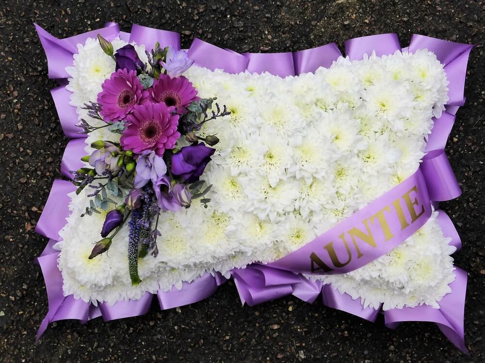 11. 18” white pillow with purple ribbon edge and sash. Germini, Freesia, Lisianthus and Veronica posy