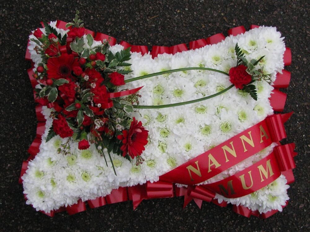 6.  18” White Pillow with red ribbon edge, red ribbon sash’s and red posies