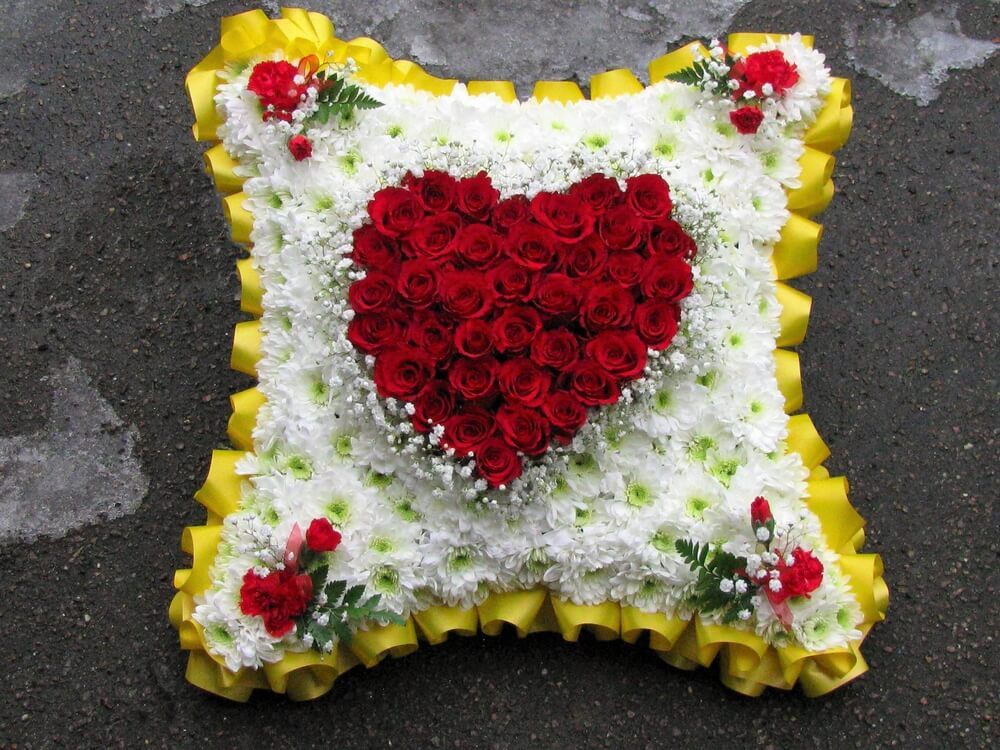 3.  18” Cushion with yellow ribbon edge, heart of red Roses to the centre with red Dianthus posies in each corner