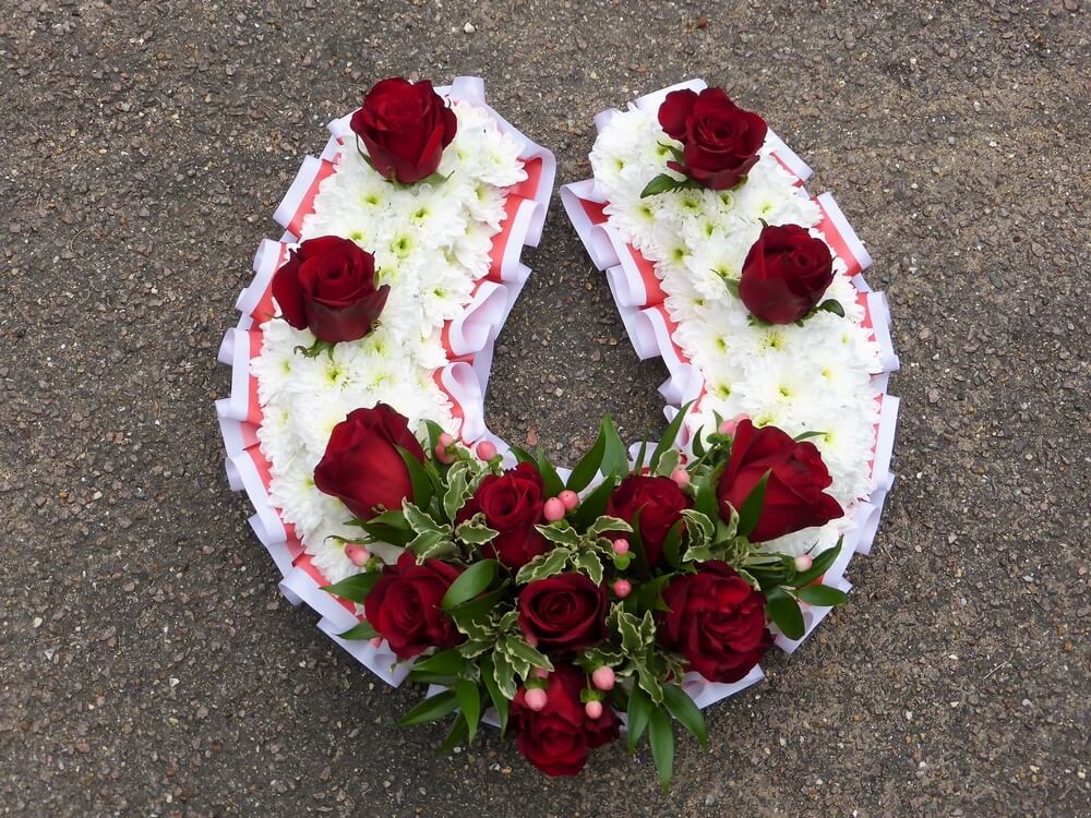 3.  Horseshoe in red and white with ribbon edging and decorated with red Roses and Berries