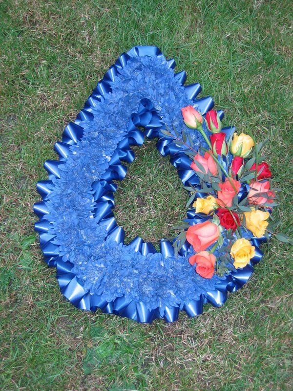 8.  Teardrop with blue flowers with blue ribbon edge and posy of red orange and yellow Roses