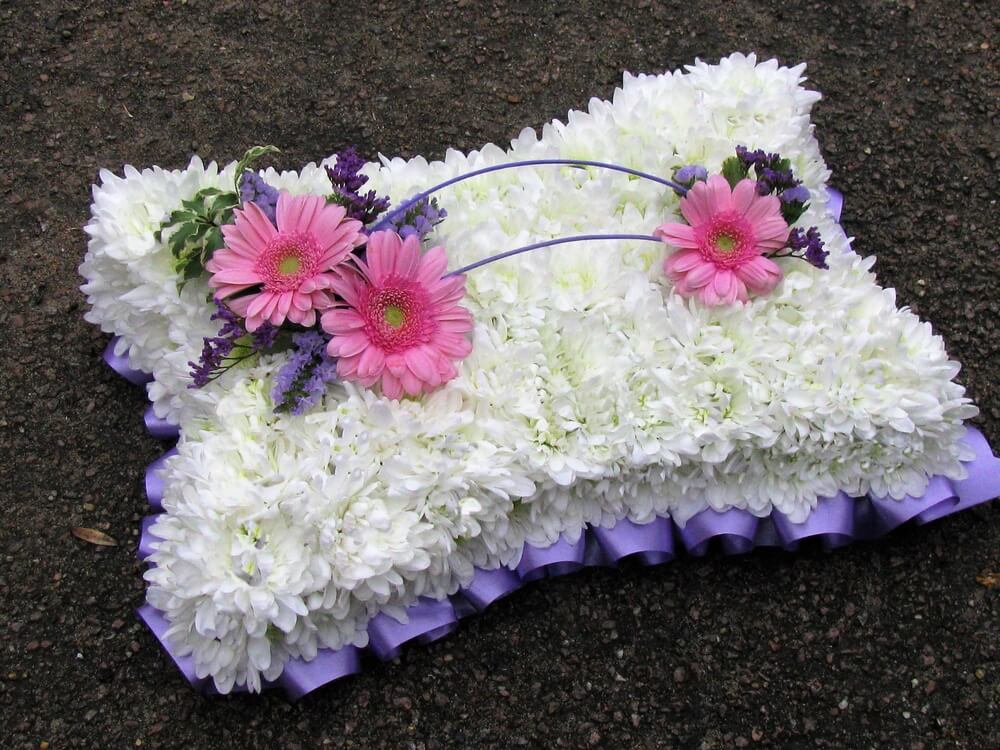5.  15” White Pillow with lilac ribbon edge and posies of pink Germinis and purple Limonium