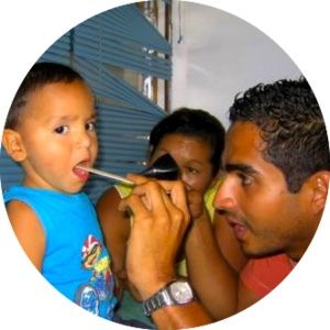 A young child has their throat examined by a doctor with a nurse looking on.