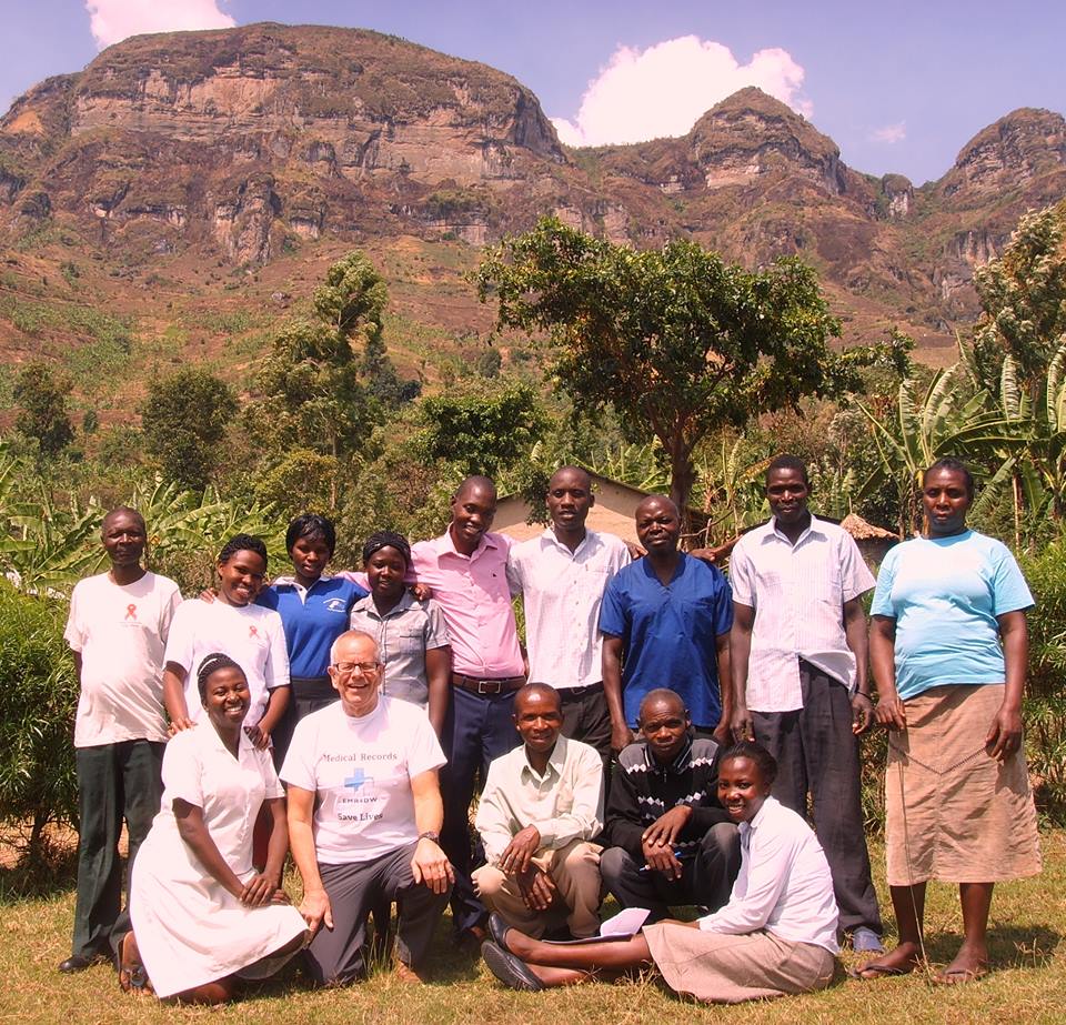 Group of people posing outdoors with a mountain backdrop in Africa.