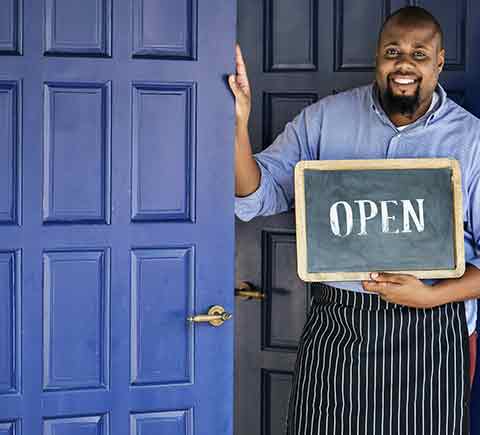 Business Insurance — Business Owner With Open Sign in Manchester, NH Business Insurance — Business Owner With Open Sign in Manchester, NH