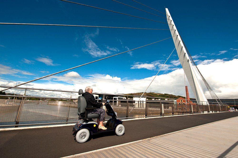 A person riding a mobility scooter on a bridge