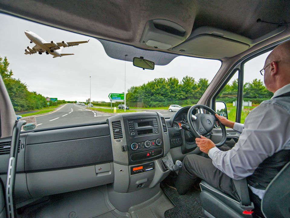 Executive Chauffeur Minibus being driven towards the perimeter of a busy airport in Bristol
