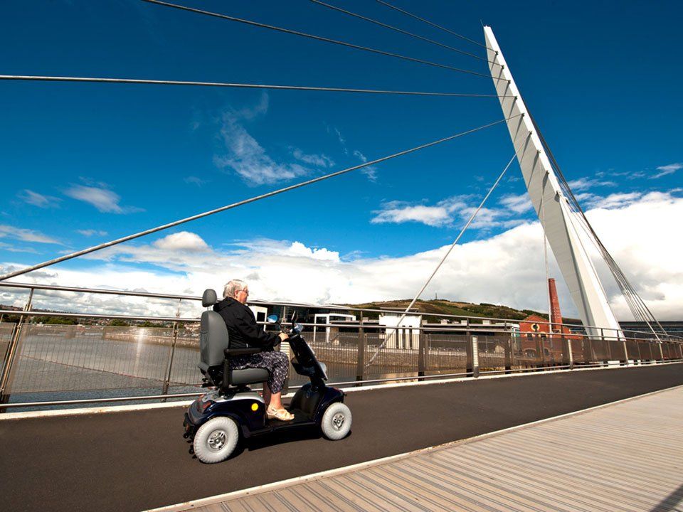 A person riding a mobility scooter on a bridge