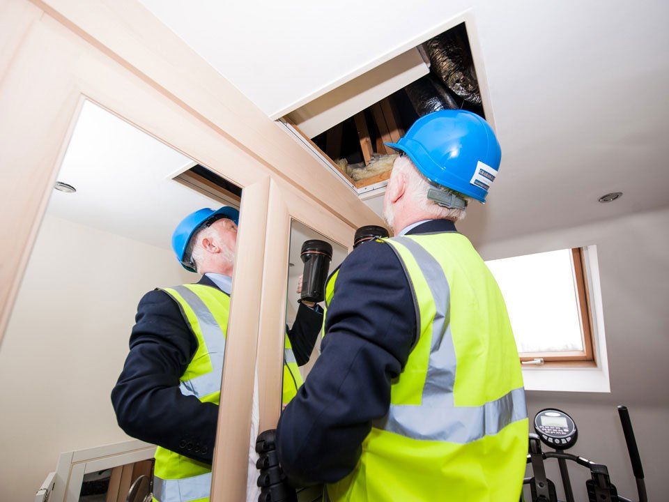 A man wearing a hard hat and safety vest looks at himself in a mirror