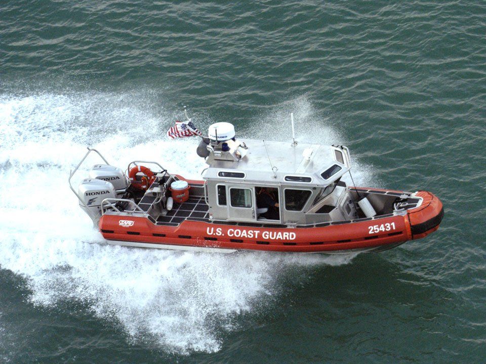 A u.s. coast guard boat is speeding through the water