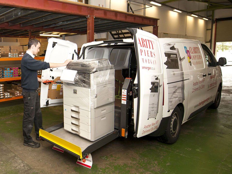 Clarity Copiers Glamorgan engineer loading Multi-Function Printer MFP onto a liveried van for delivery