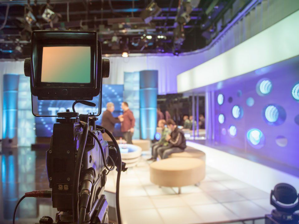 A camera is pointed at a group of people in a tv studio