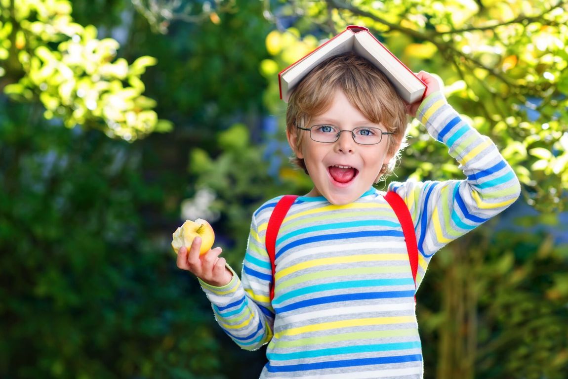 bambino con occhiali da vista e libro sulla testa