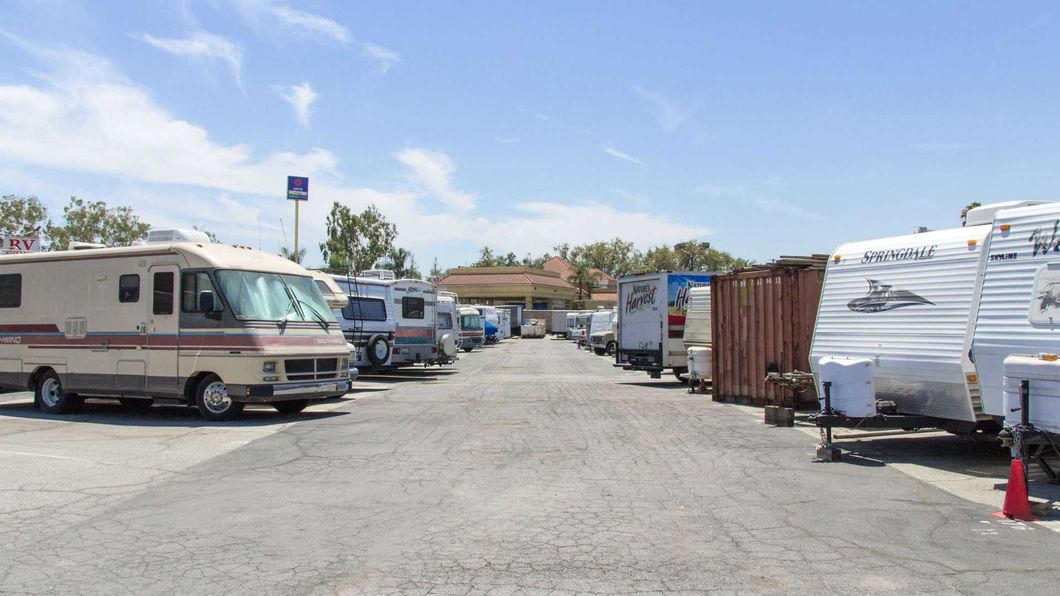 RV campground with several parked motorhomes and trailers on a sunny gravel lot