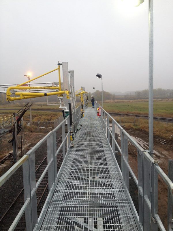 a metal walkway leading to a train track on a foggy day .