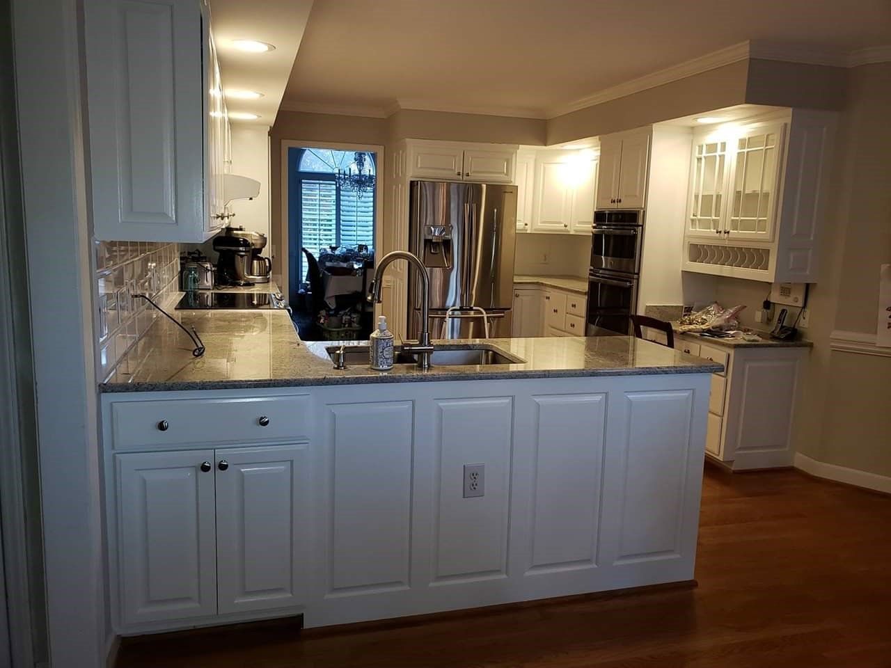 a kitchen with white cabinets , granite counter tops , a refrigerator and a sink .