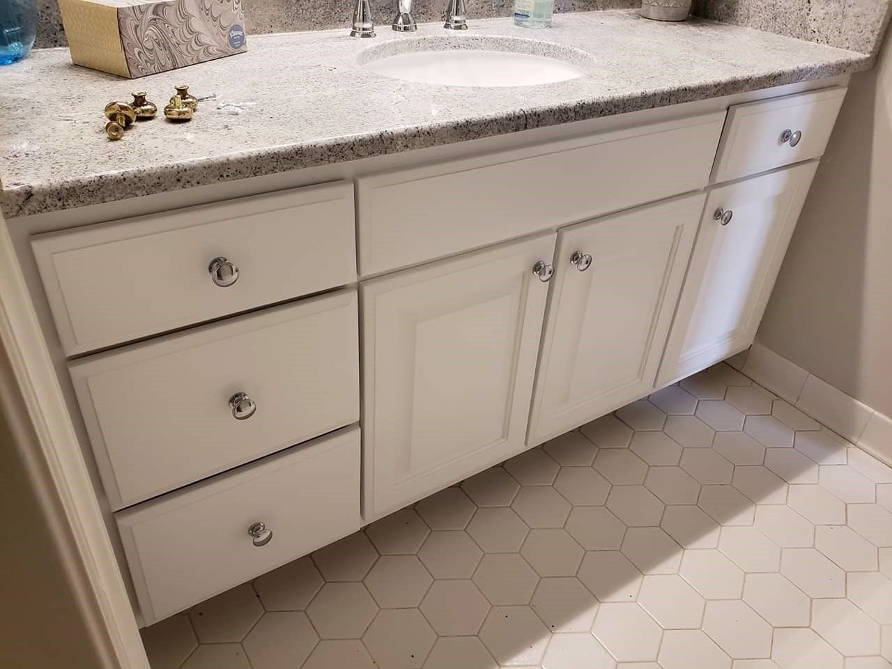 a bathroom vanity with white cabinets and drawers and a sink