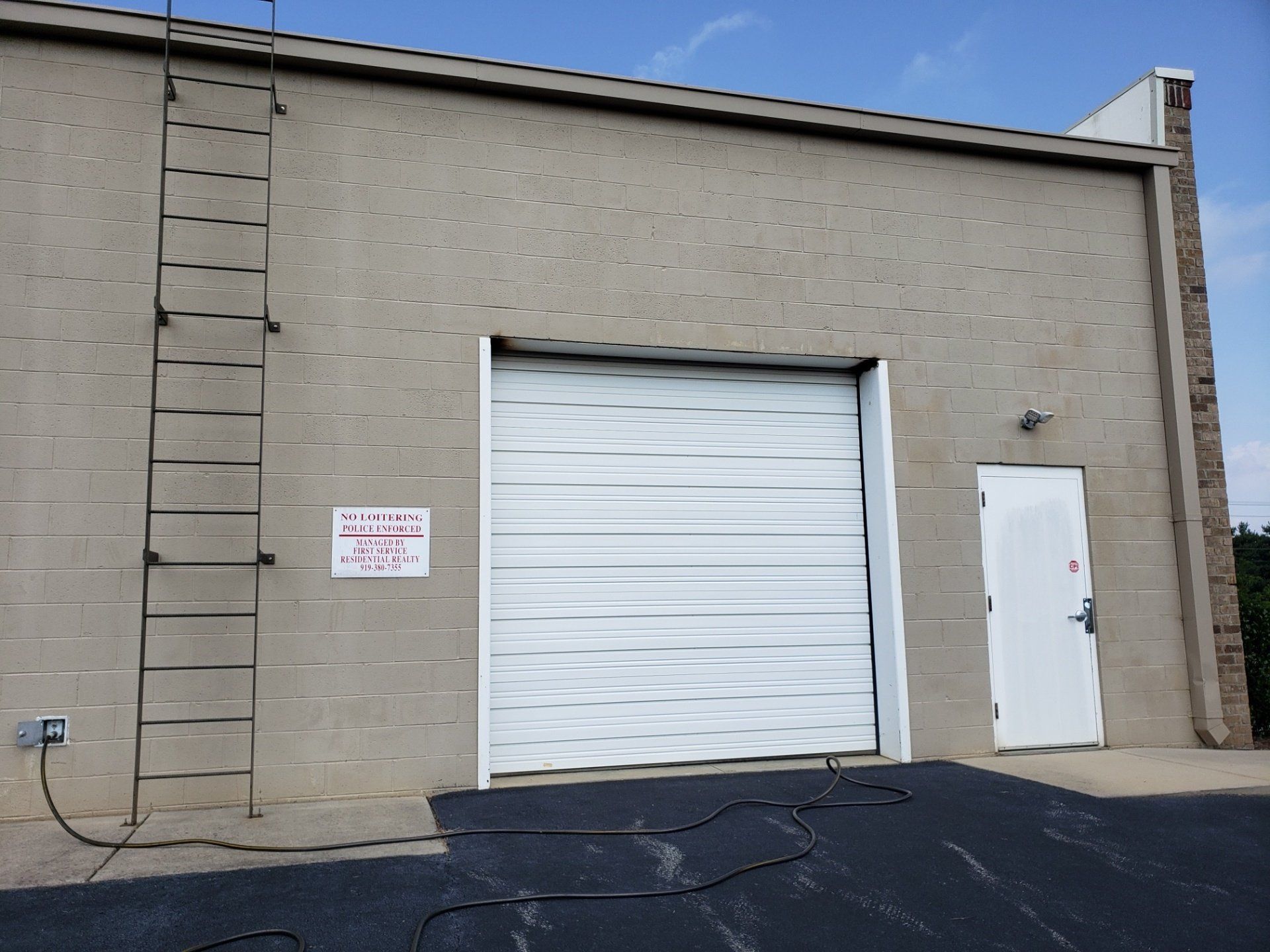 a building with a white garage door and a ladder on the side