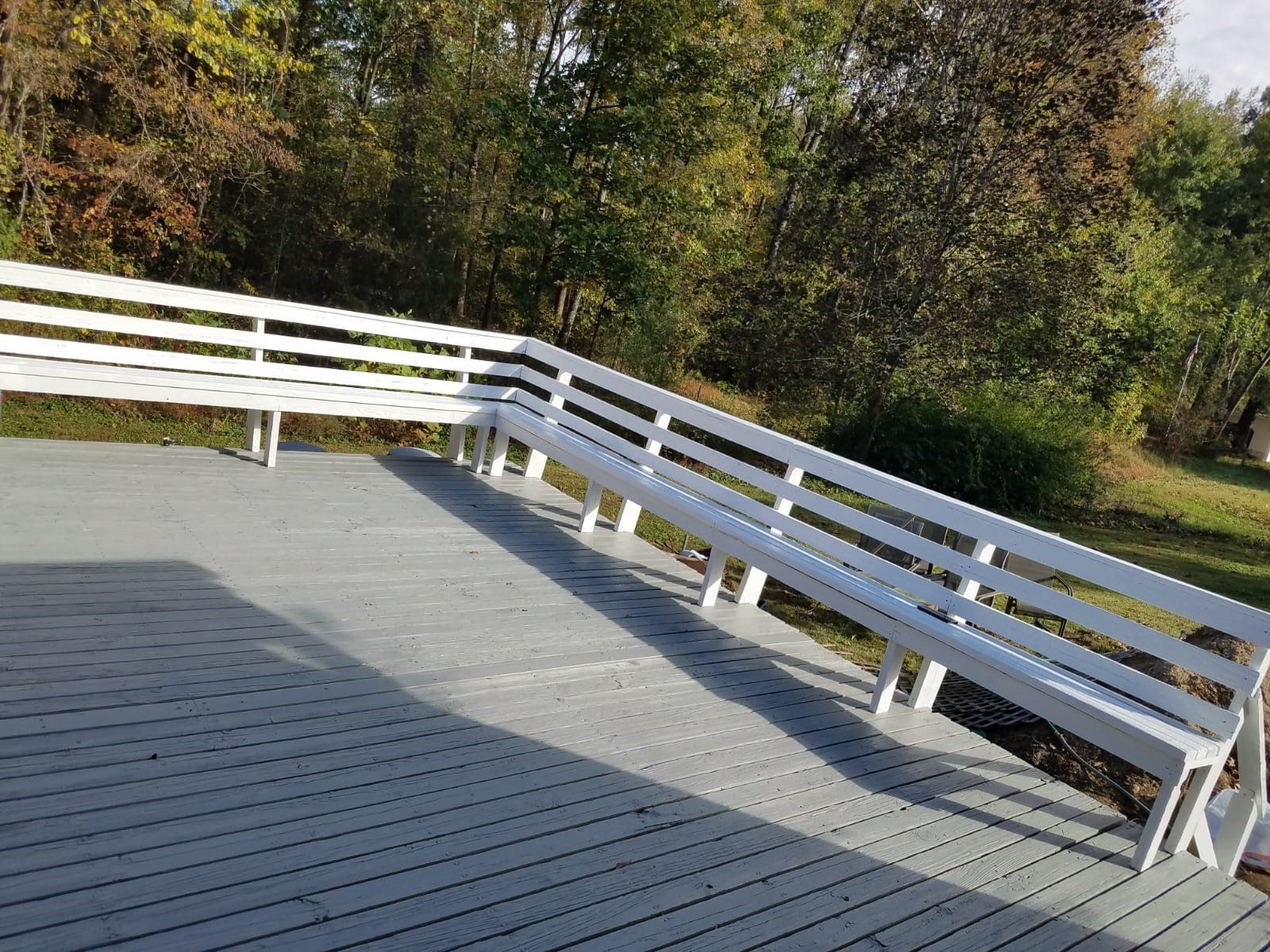 a wooden deck with two white benches and a railing .