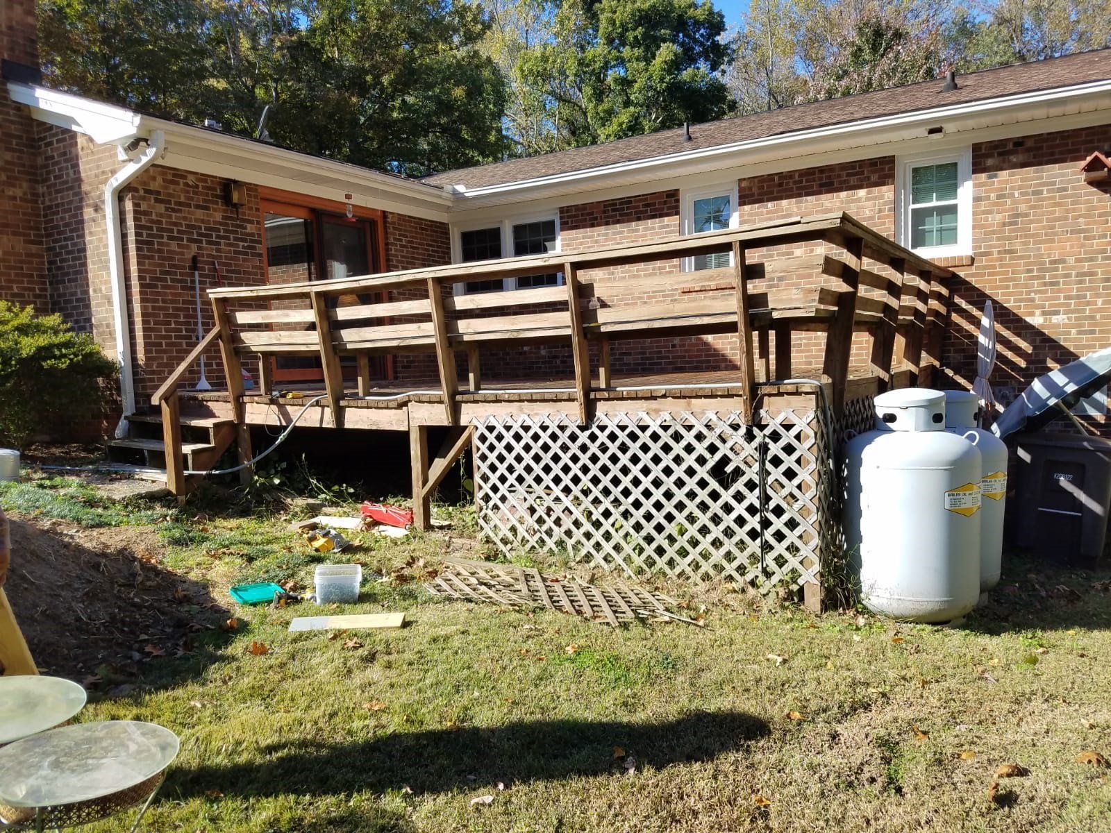 a house with a wooden deck and a propane tank in front of it .
