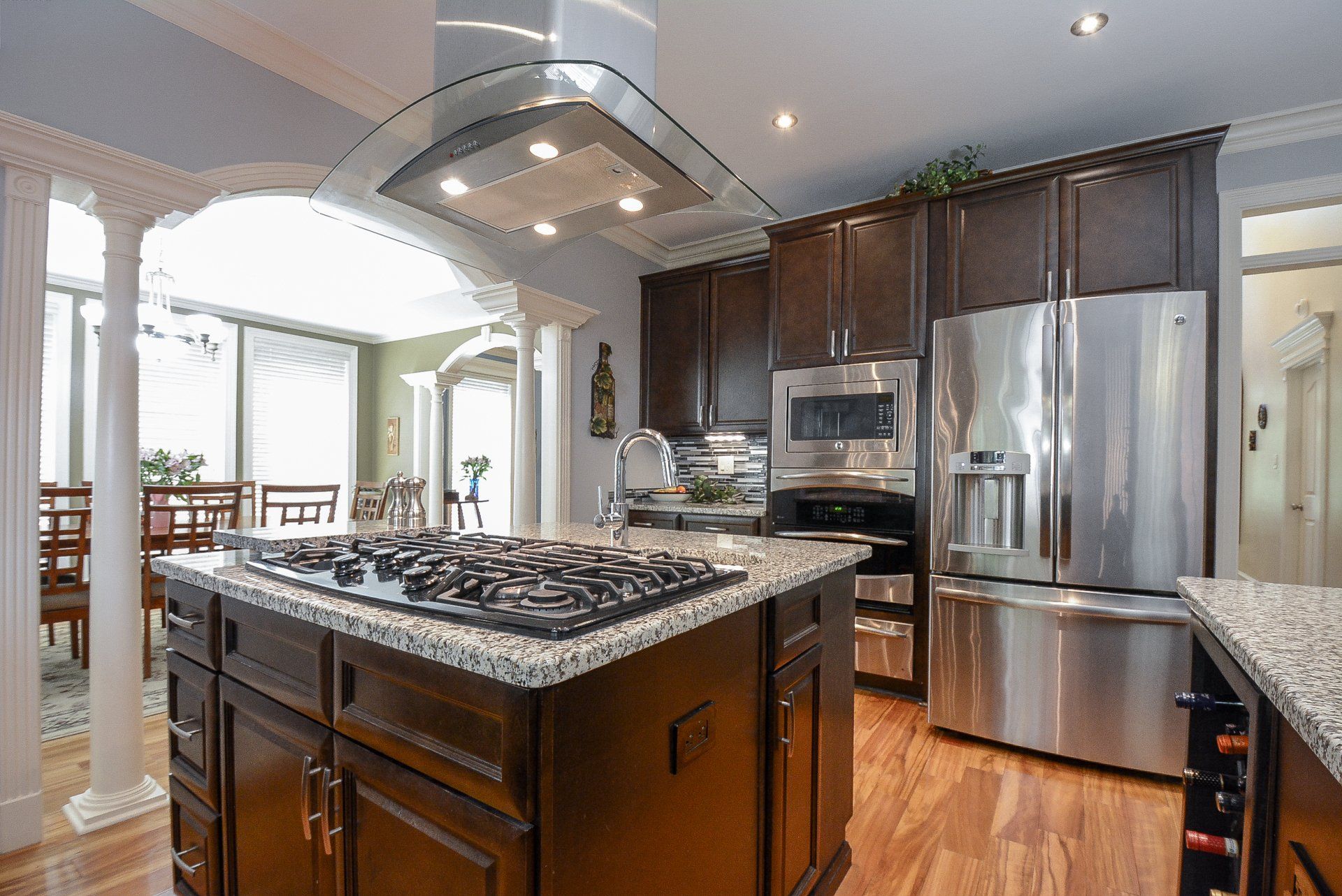 Kitchen with dark wood cabinets, stainless steel appliances, and a granite countertop island with a gas cooktop.
