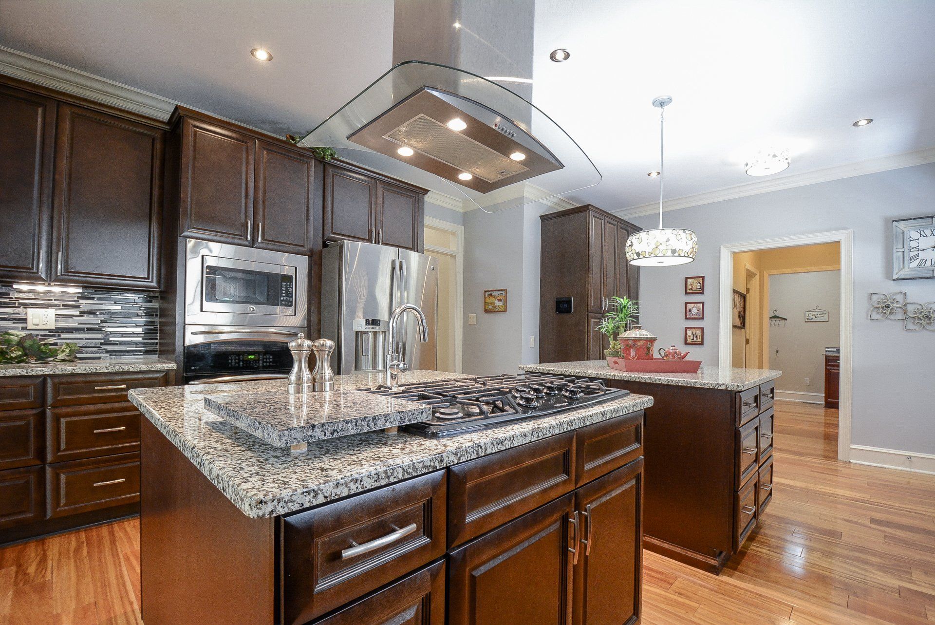 Kitchen with dark wood cabinets, granite countertops, stainless steel appliances, and a stove top island.