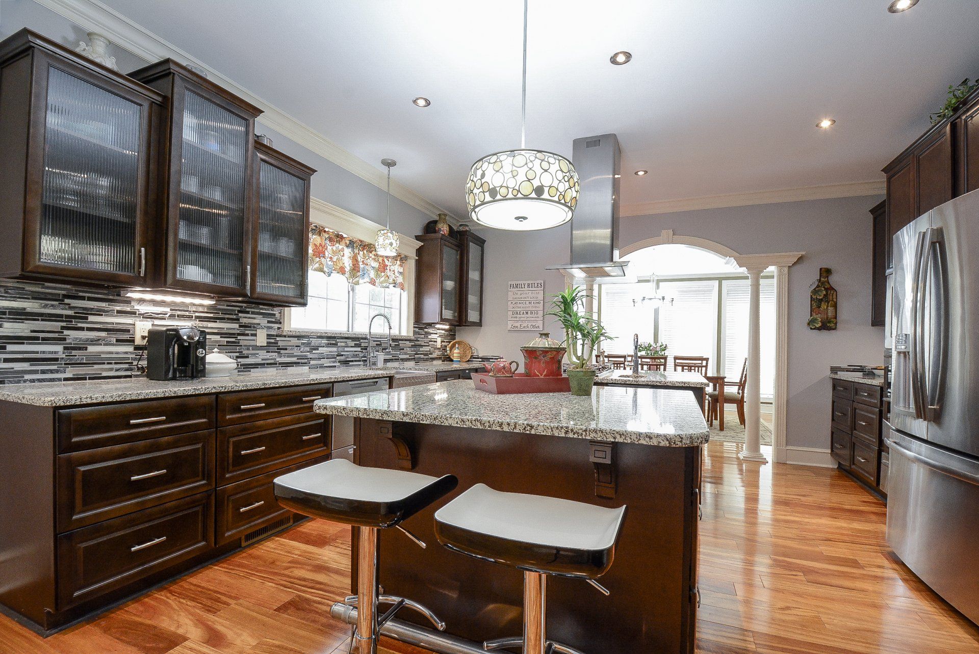 Kitchen with dark cabinets, island with stools, and stainless steel appliances.