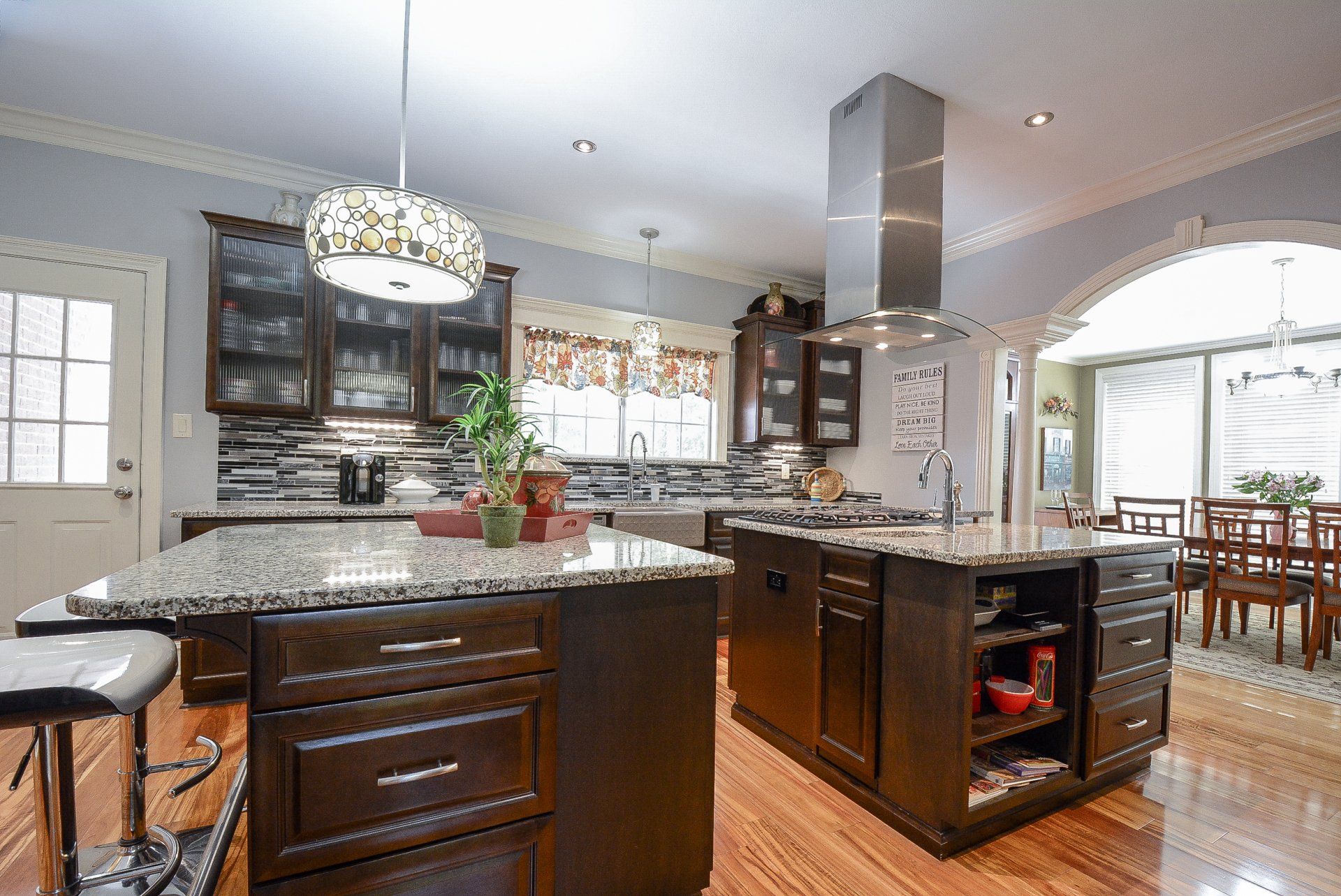 Spacious kitchen with two dark wood islands, granite countertops, and stainless steel range hood.
