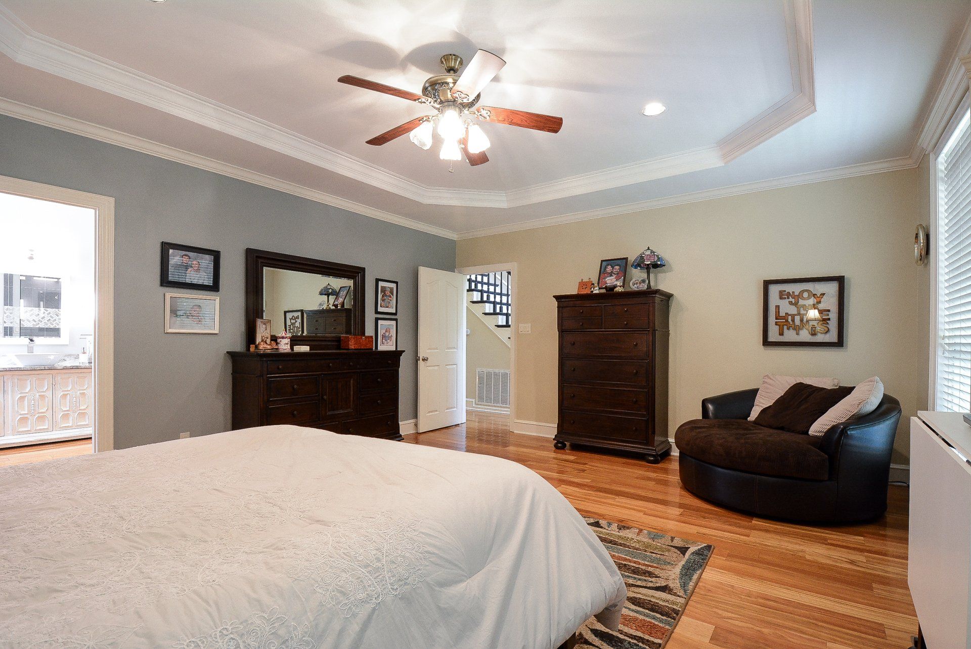 Bedroom with bed, dresser, chair, and wood floor, in light blue and green walls.
