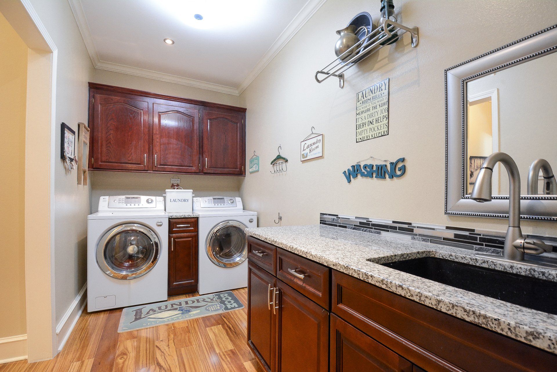 Laundry room with washer, dryer, cabinets, sink, and countertop.