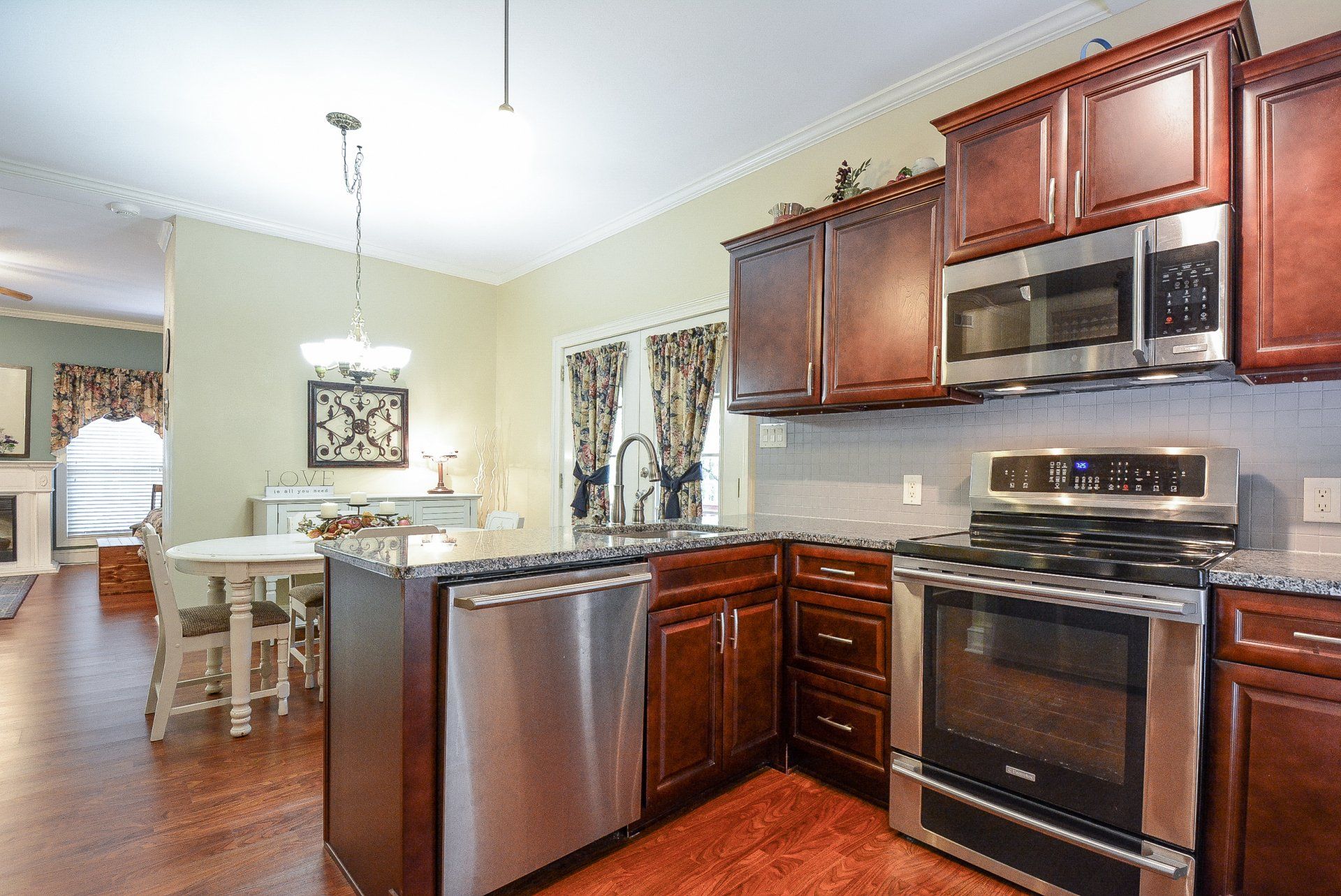 Kitchen with stainless steel appliances, dark cabinets, granite countertops, and a view into a dining area.