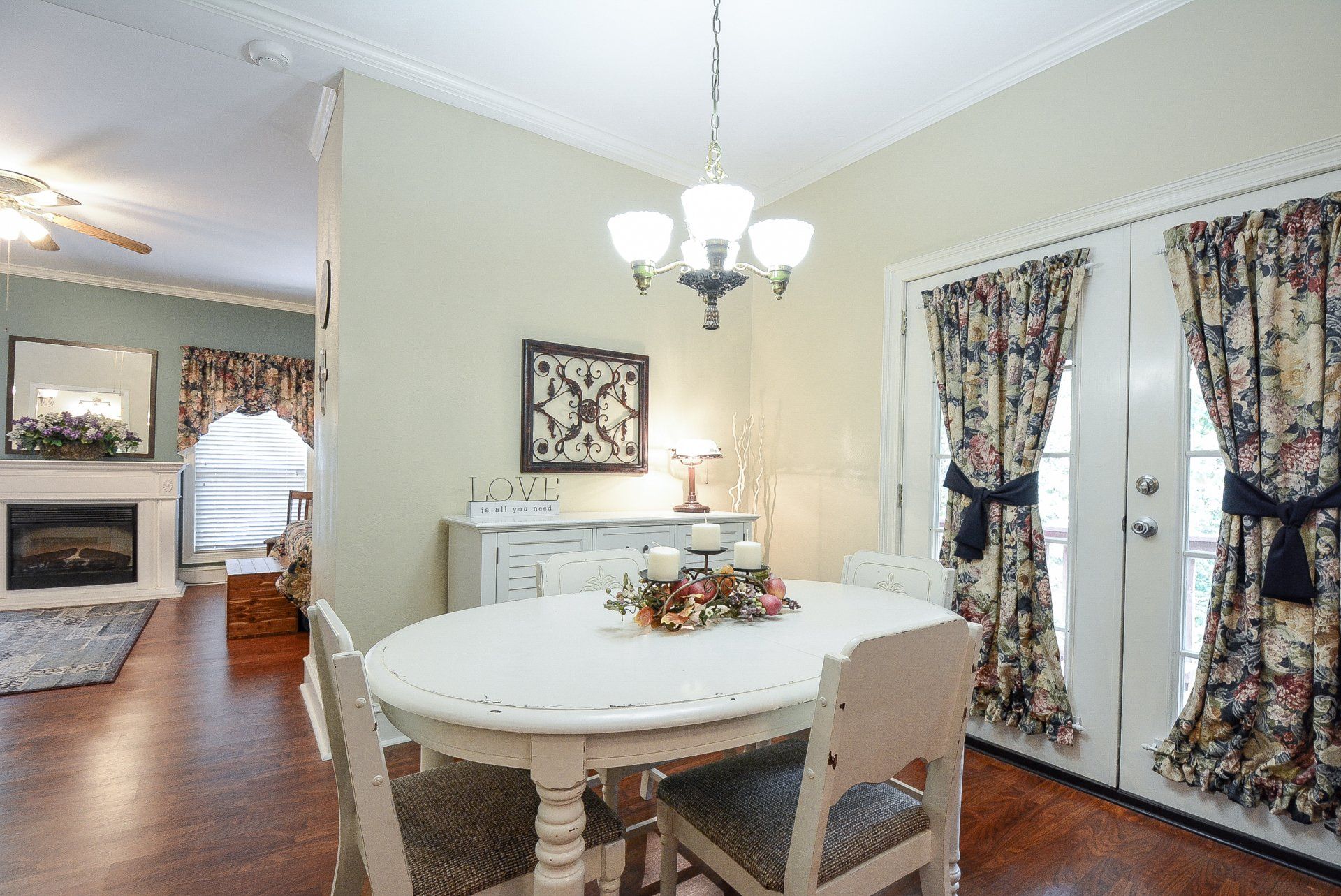 Dining room with a white table, floral curtains, and French doors.