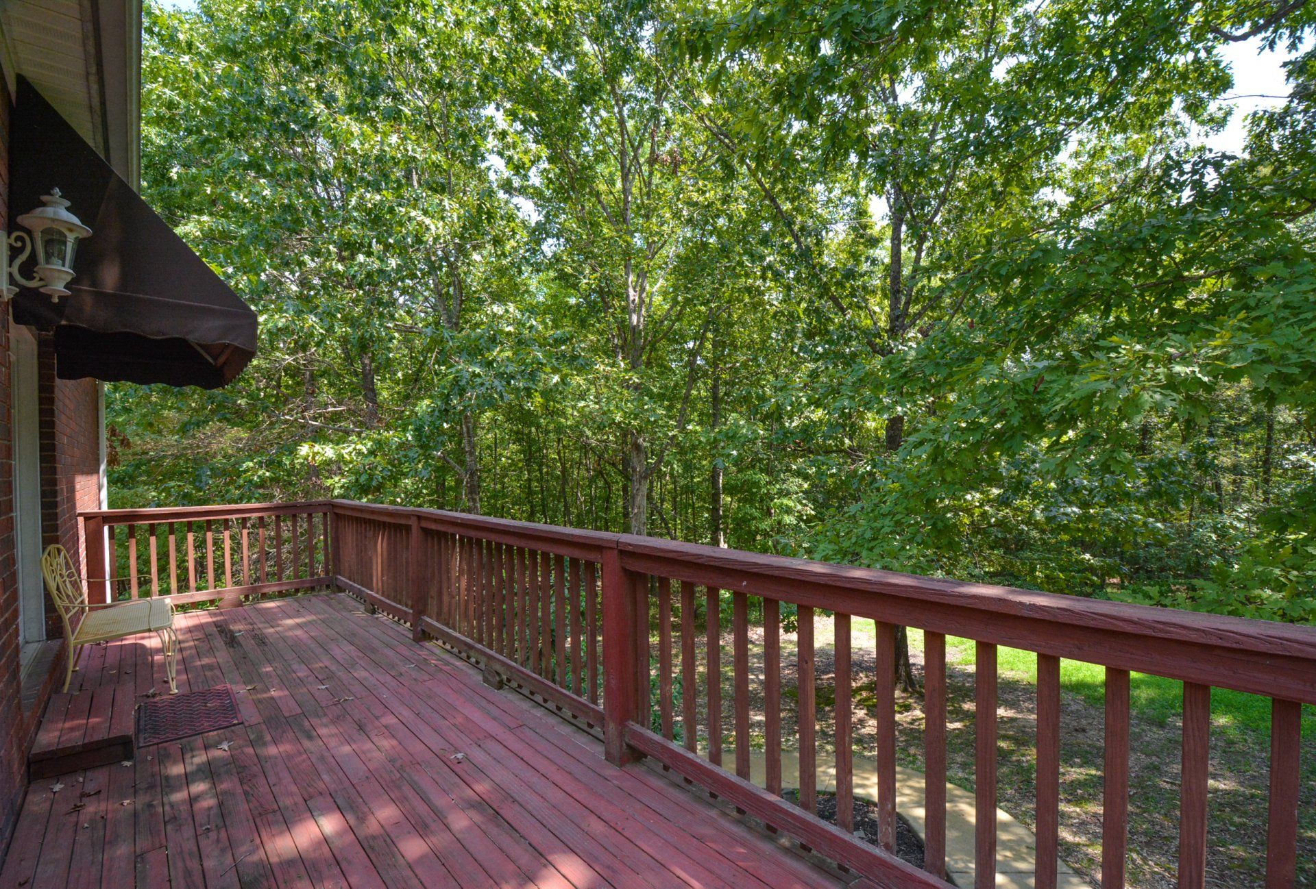Red wooden deck with railing and green forest background.