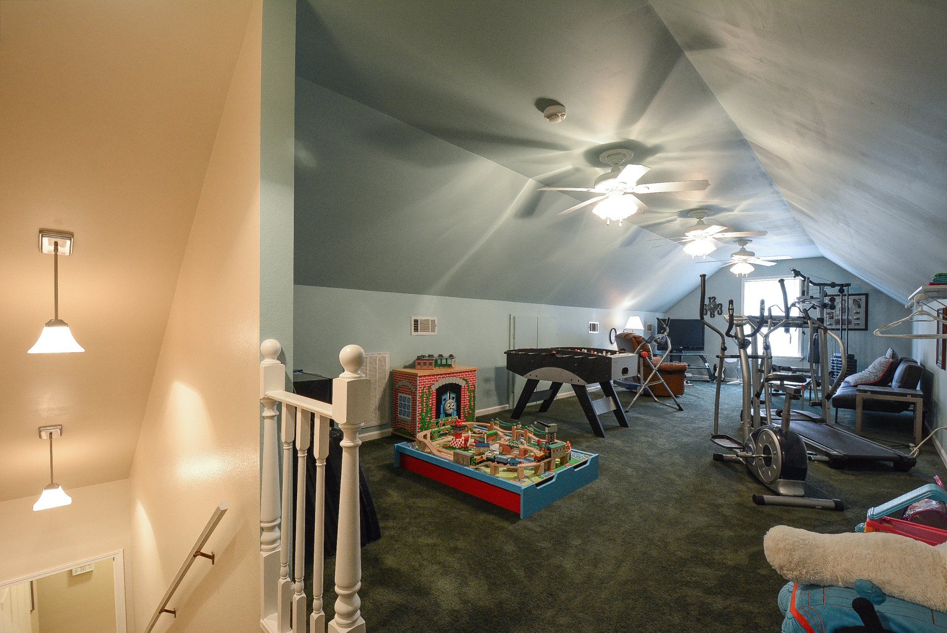 Stairway leading up to a large game room with exercise equipment, foosball, and a Lego play area.