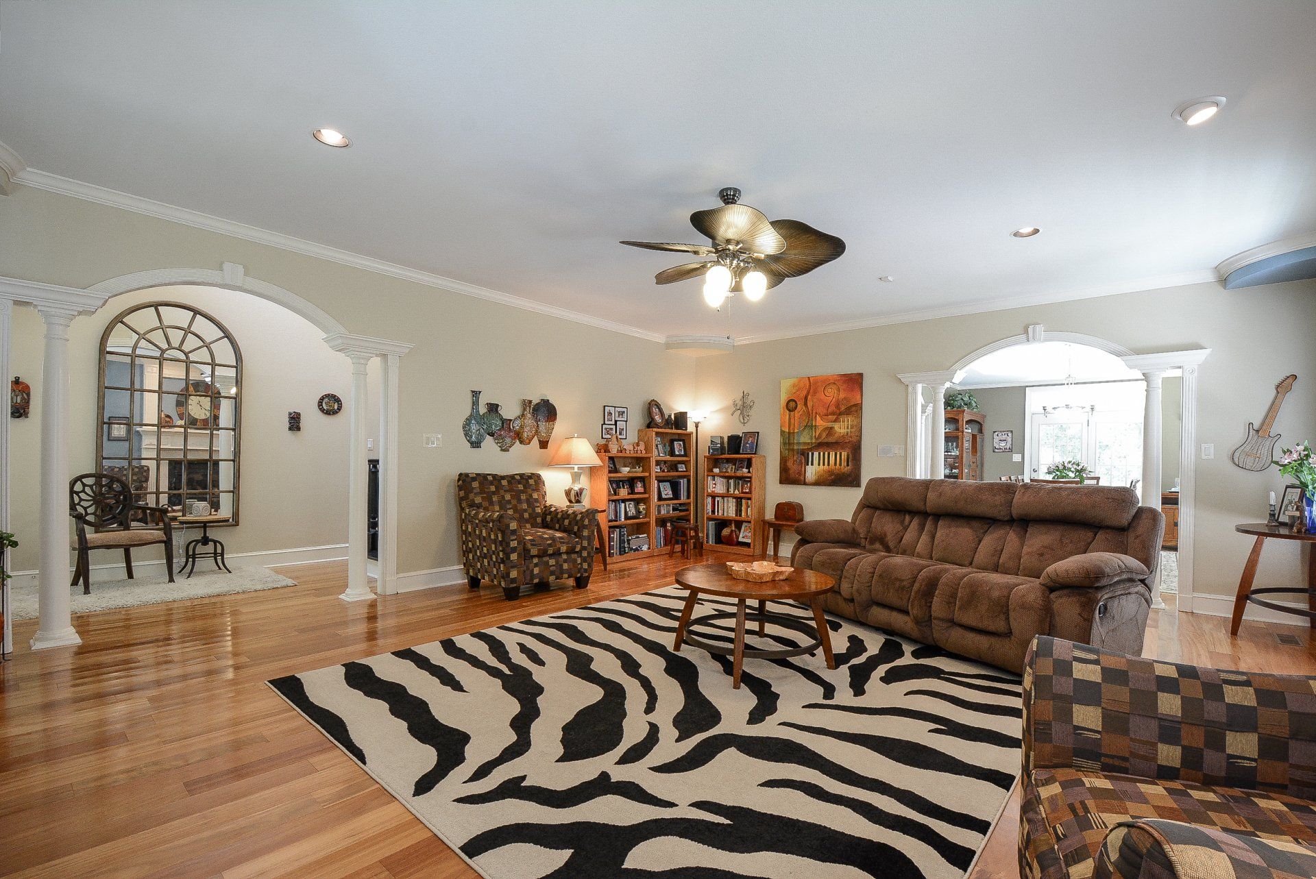Living room with zebra rug, brown sofa, bookshelves, and ornate archways.