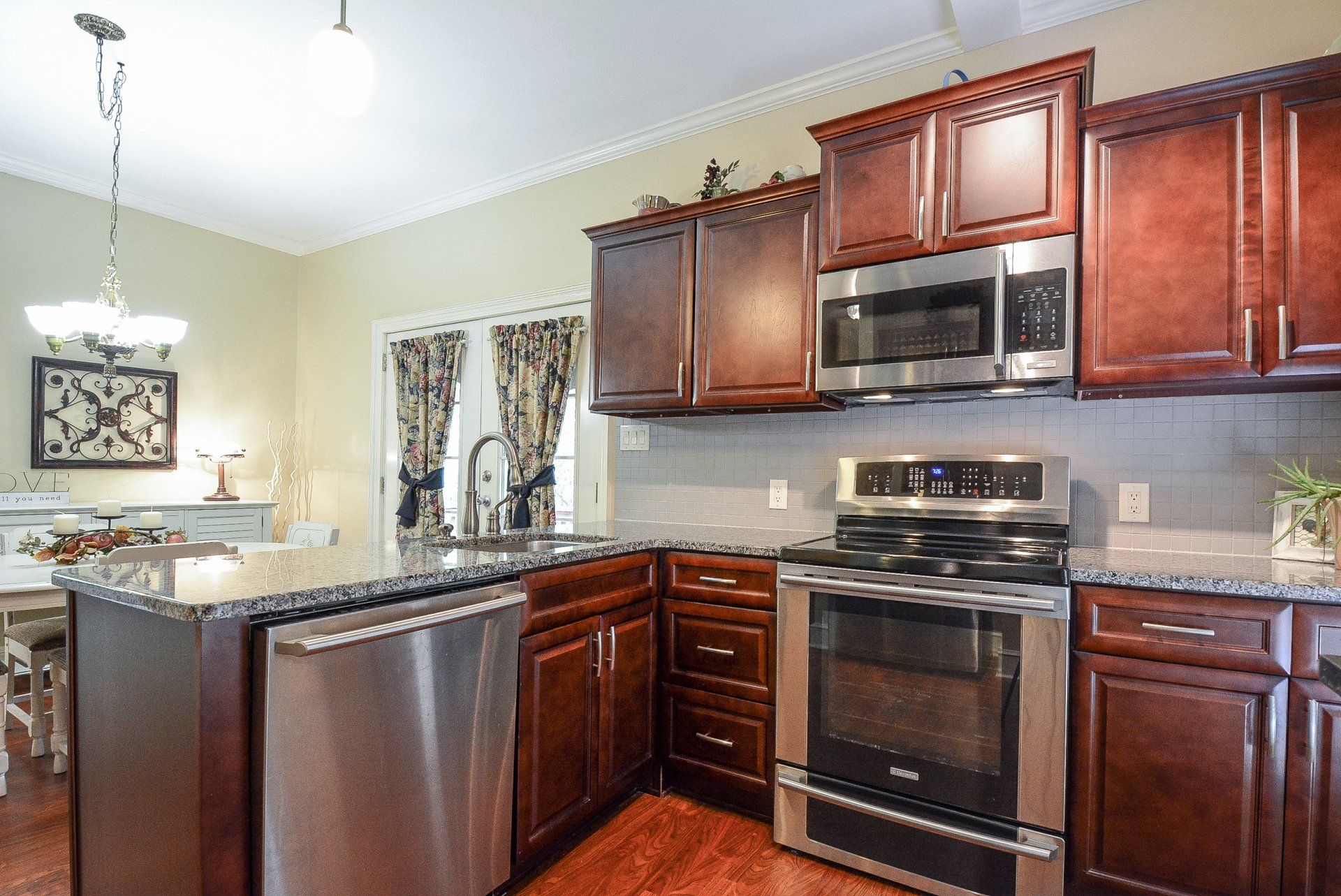 Kitchen with stainless steel appliances, dark cabinets, and granite countertops.