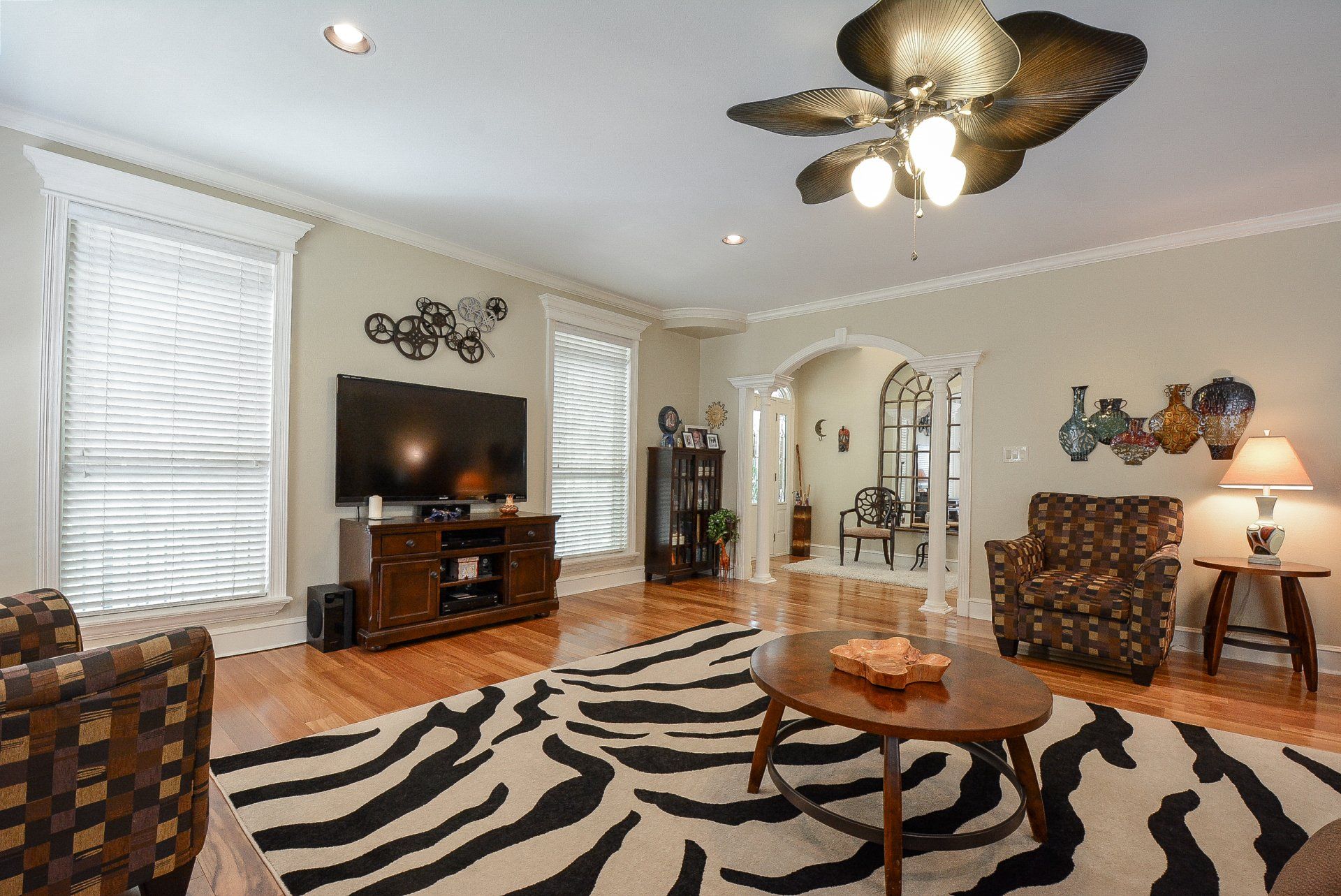 Living room with zebra rug, TV, furniture, and a decorative ceiling fan.
