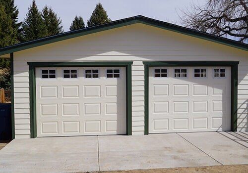 Two-car garage with white doors, green trim, and concrete driveway.