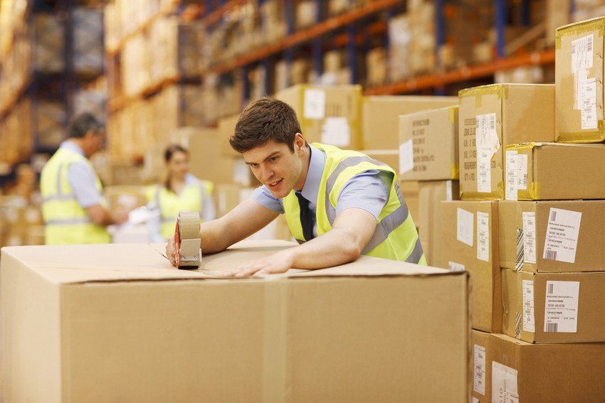 Worker taping box in warehouse