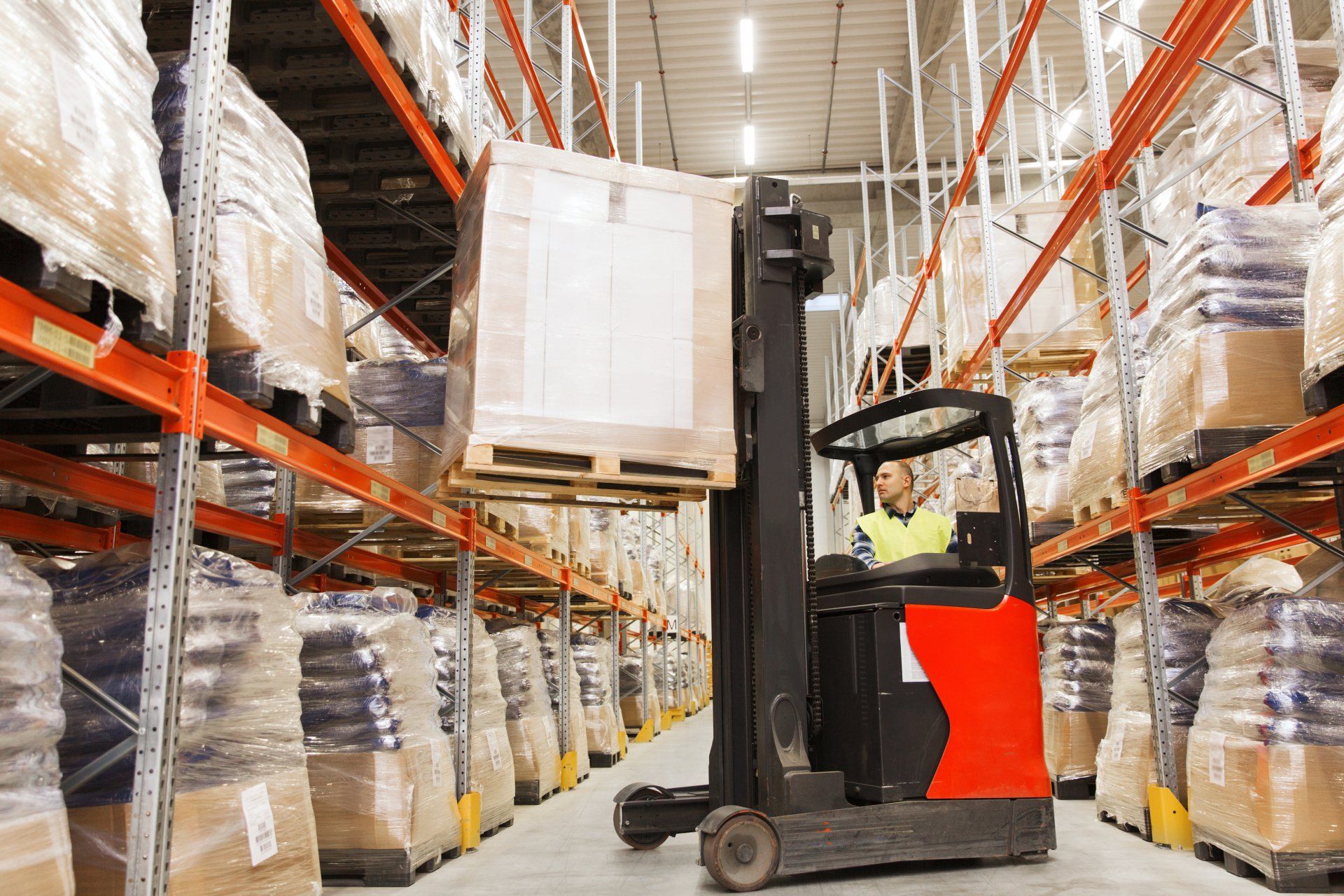 A man is driving a forklift in a warehouse.