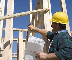 Construction worker holding blueprint, smiling — Building Inspection in Plainville, CT