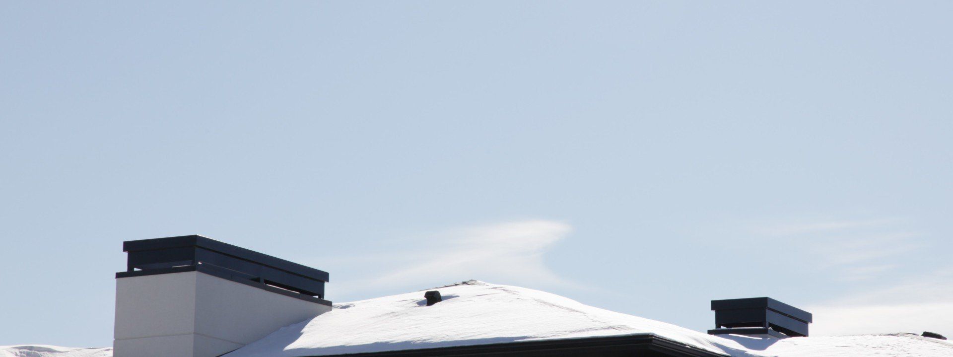 a snowy roof with two chimneys on it