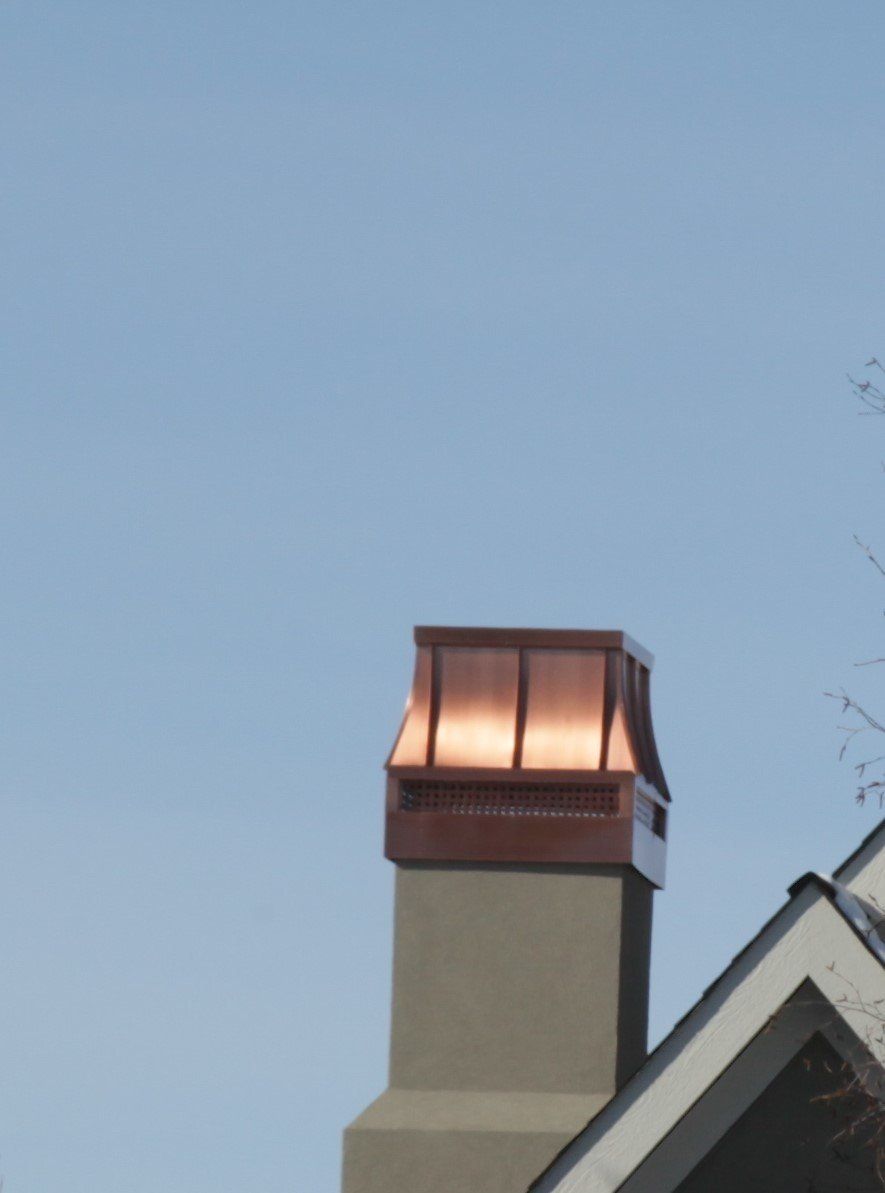 a copper chimney on top of a house with a blue sky in the background
