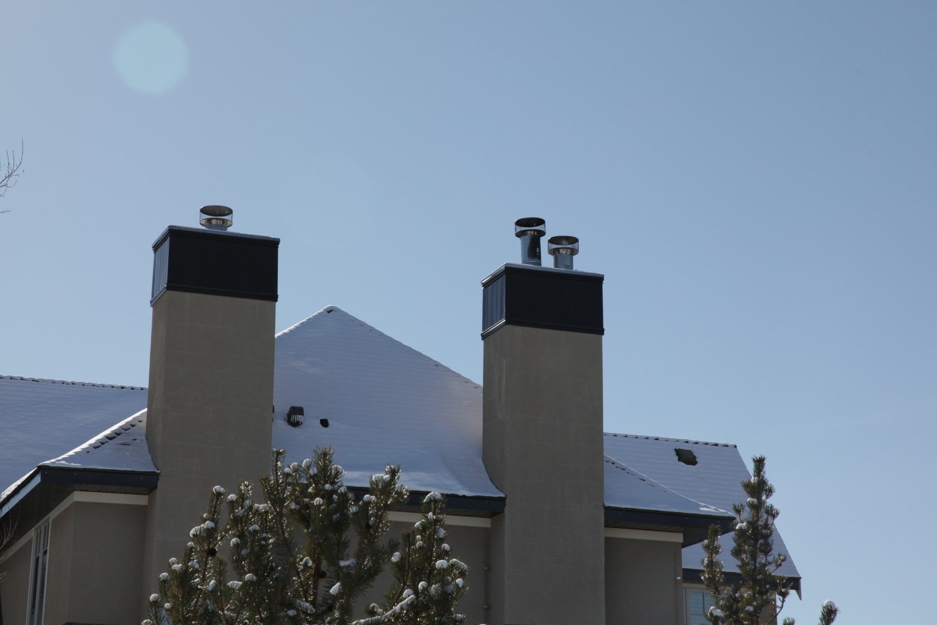 two chimneys on top of a building with snow on the roof