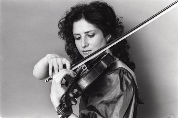 young madeleine mitchell playing violin on black and white background