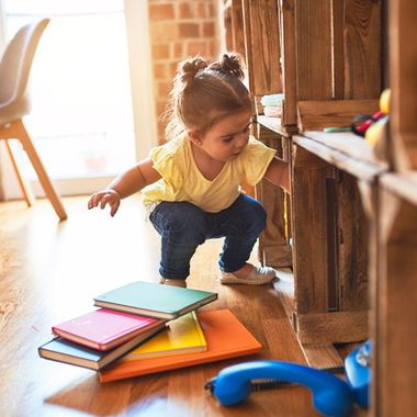 Cute Girl Playing with Books — Cheyenne, WY — The Backyard Child Care Center