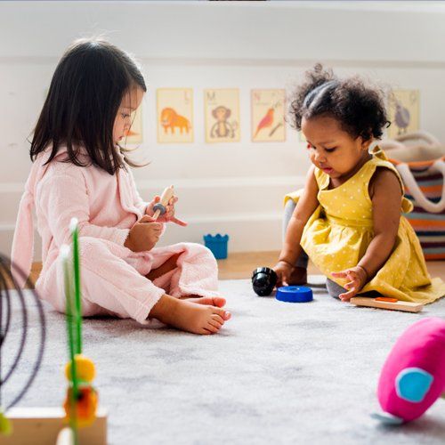 Baby Girls Playing Together on the Floor — Cheyenne, WY — The Backyard Child Care Center